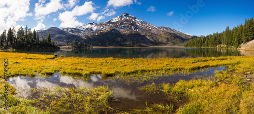 Fototapeta Naklejka Na Ścianę i Meble -  Fall color creeps into the lakeside vegetation below a tall volcanic mountain.