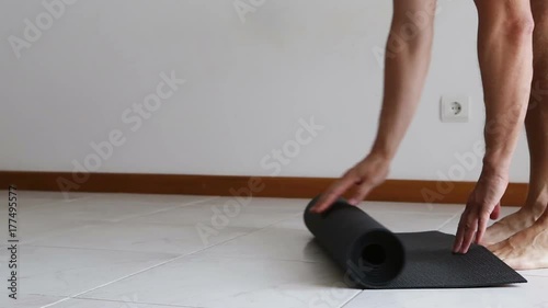 Man untwists a gym mat for training. photo