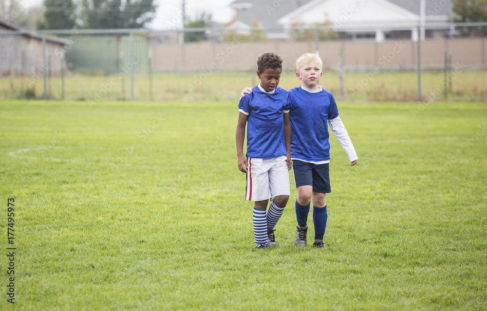 Naklejka premium Two soccer teammates walking off the field after a loss. Concept photo of encouragement from friends after disappointment from a loss