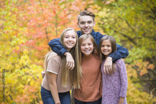 Beautiful Portrait of smiling happy teen kids outdoors. Four siblings standing together for a cute picture on a warm fall day photo