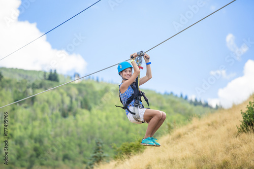 Happy smiling teen girl riding a zip line ride while on family vacation