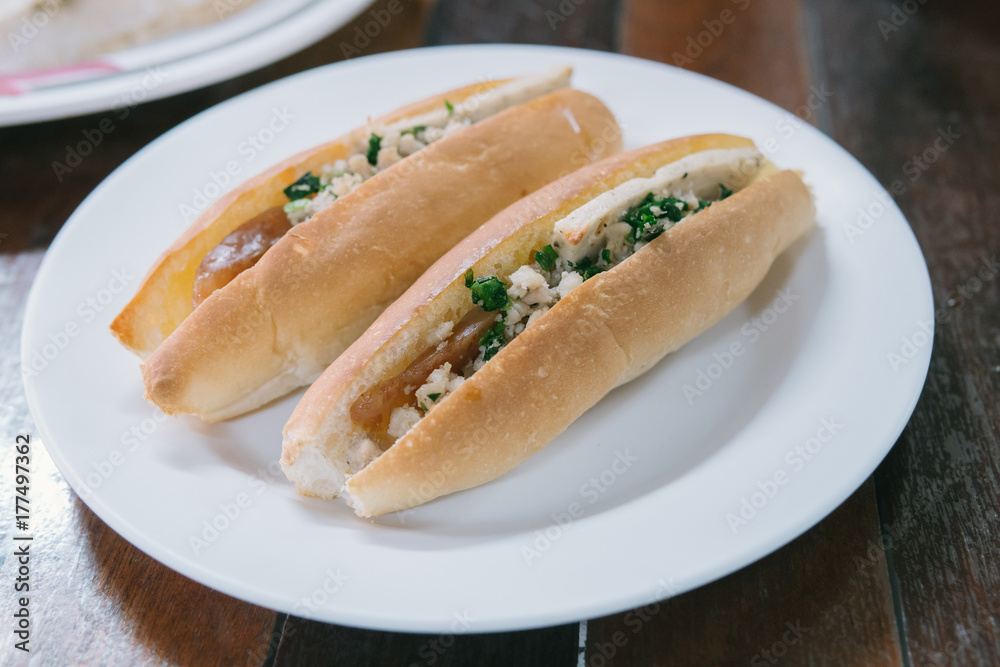 Vietnam Bread stuffed with Chinese sausage and pork on white plate. Vietnam Bread stuffed with Chinese sausage and pork on white plate.