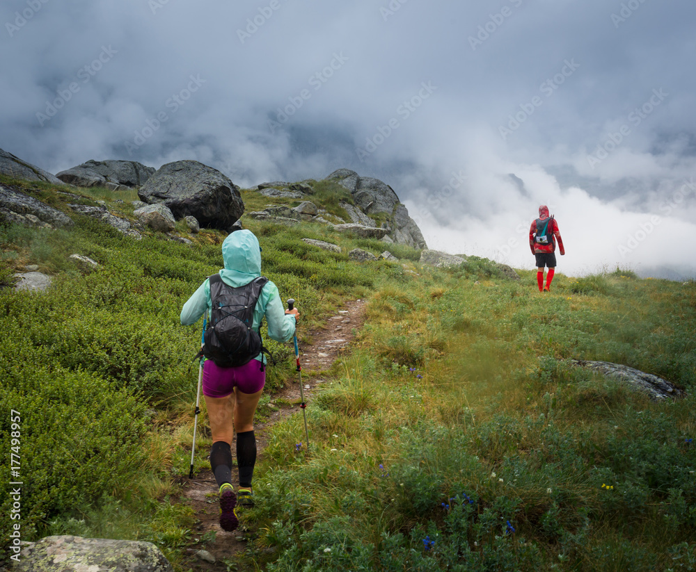 A group of athletes on a rainy day runs down the path towards the fog. Altay, Russia