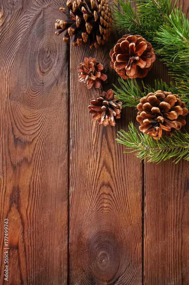 Fototapeta premium Christmas background. Fir tree branches and cones on a wooden backdrop. Copy space. Top view.