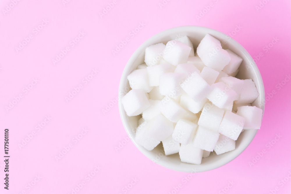 Closeup sugar cubes on bowl with pink background, health care concept Closeup sugar cubes on bowl with pink background, health care concept