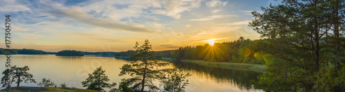 Panorama picture taken in Sweden with sunset over a lake and beautiful glow from the sun