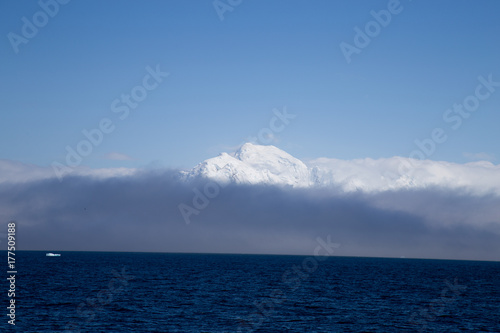 A mountain top reaches over the mist and clouds in Antarctica.