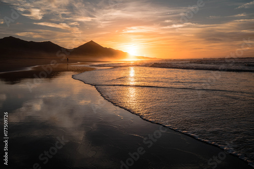 Amazing beach sunset with endless horizon and hills  reflection in the background
