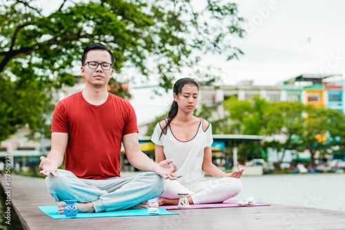 Asian couples is exercise. The man is teach yoga to women.