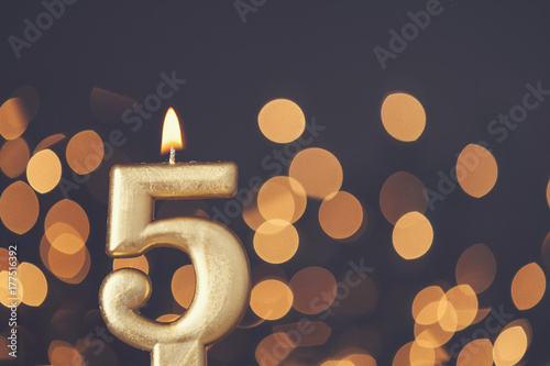 Gold number 5 celebration candle against blurred light background photo