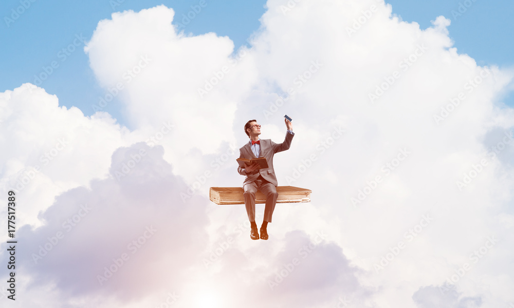 Young businessman or student floating in blue sky and studying the science Young businessman or student floating in blue sky and studying the science