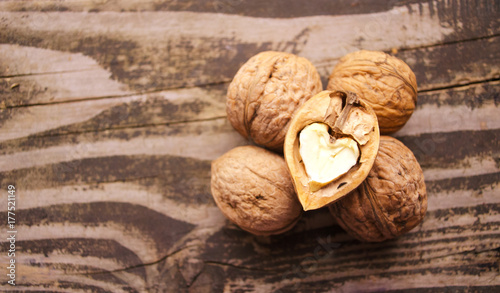 Walnuts on a textured wooden table. Assortment of nuts isolated on rustic old wooden background and splintered walnut with heart-shaped core.