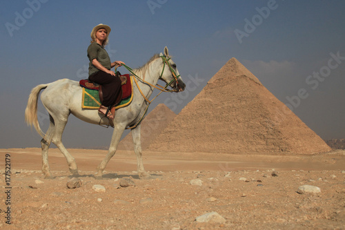 Frau steht alleine mit ihrem Pferd vor den Pyramiden in   gypten