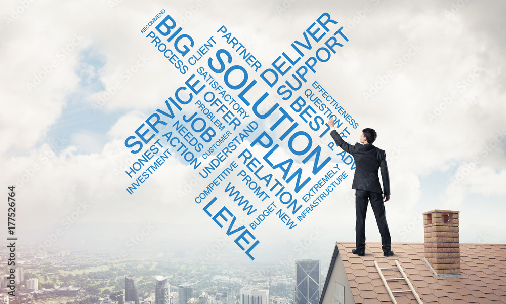 Young businessman standing on house roof and writing leadership Young businessman standing on house roof and writing leadership