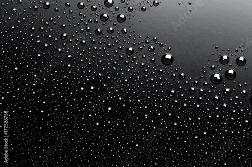 Close- up of water drops on black surface, background.