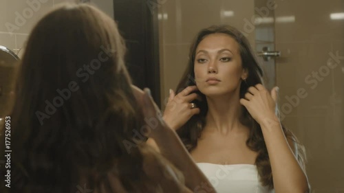 Well-groomed girl corrects her hair in front of the mirror