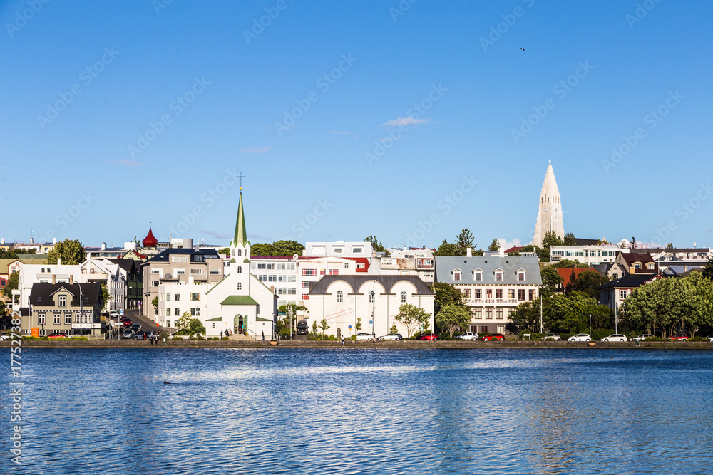 Reykjavik cityscape, with the bell tower of the Hallgrimskirkja church, viewed from across the Tjornin lake in the heart of Iceland capital city on a sunny summer day.
