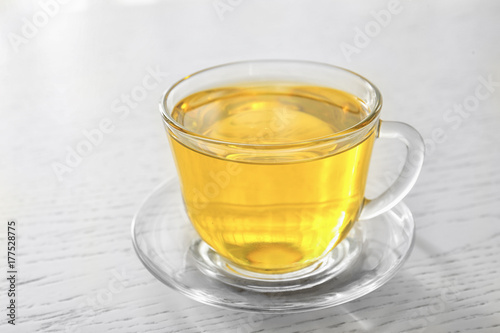 Glass cup with oil on light wooden background