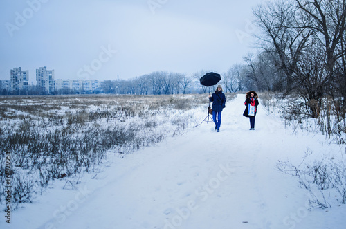 photographer taking pictures of girl in the winter in the field. cold