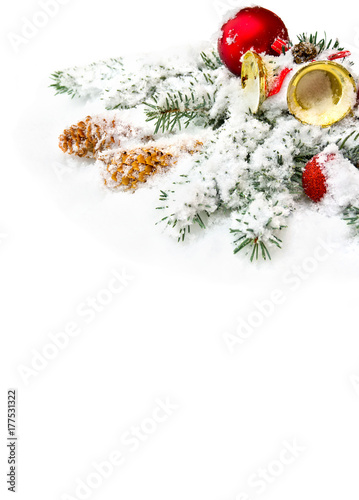 Christmas decoration. Branch christmas tree, christmas bells, red balls and cones spruce on snow on white background with space for text.