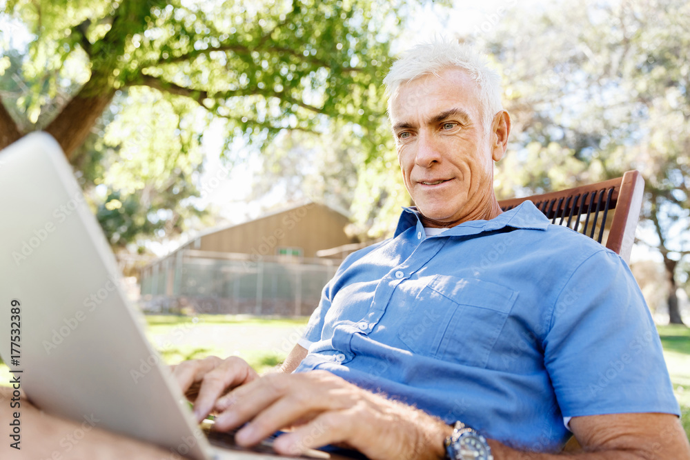 Senior man with notebook sitting in the park Senior man with notebook sitting in the park