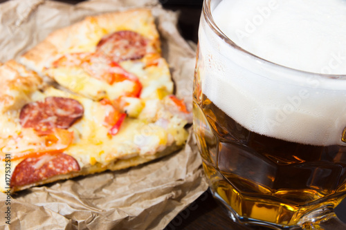 Light beer in glass and fragrant Italian pizza.