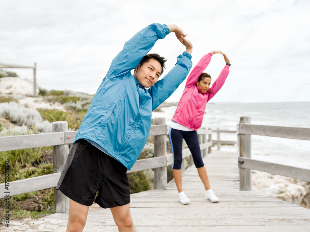 Fototapeta premium Young couple at the seaside doing exercises