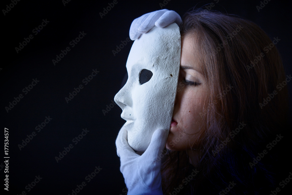 brunette girl is holding a theater mask in front of their face Stock Photo  | Adobe Stock