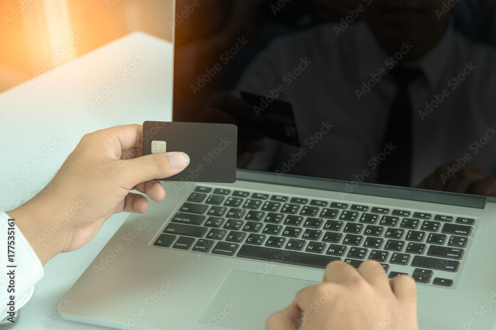 Hold a mobile credit card and use a laptop. Online shopping in the daytime Hold a mobile credit card and use a laptop. Online shopping in the daytime