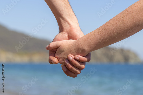Couple hands held together on a natural sea background © OlegD