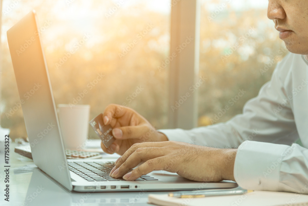 Hold a mobile credit card and use a laptop. Online shopping in the daytime Hold a mobile credit card and use a laptop. Online shopping in the daytime