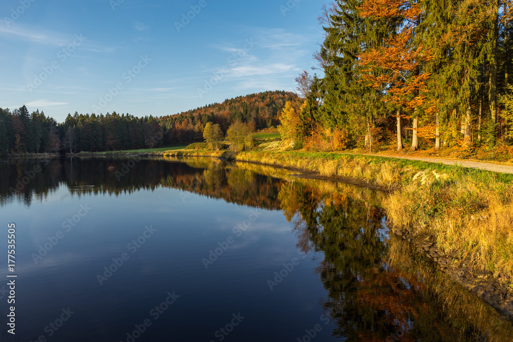 Autumn colours and reflection of the trees in a smooth lake in Germany.