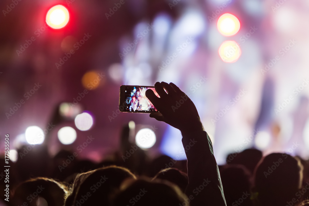 Hand with a smartphone records live music festival