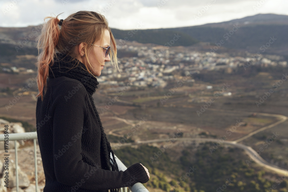 A young woman looks sadly at the mountain range. Israel