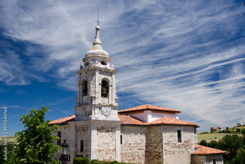 Old stone church in spain with blue sky and some clouds in the background
