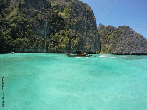 Small wooden long tail boat is heading to the beauty of emerald sea in the southern of Thailand. © Nattakarn