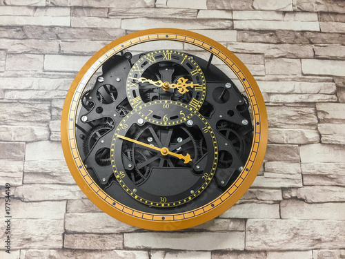 Vintage clock hanging on brick pattern wall background.