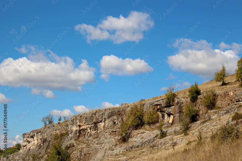Landscape with beautiful fluffy clouds over autumn rocky ridges
