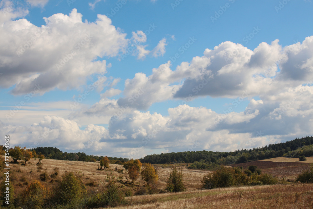 Landscape with beautiful fluffy clouds over autumn field Landscape with beautiful fluffy clouds over autumn field
