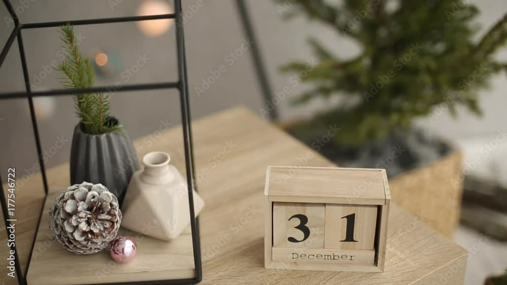 Stylish christmas scandinavian interior details. Comfort home with nordic new year's eve decor. Fir branches in vase, wooden cube calendar with December 31st figures and minimalistic christmas tree