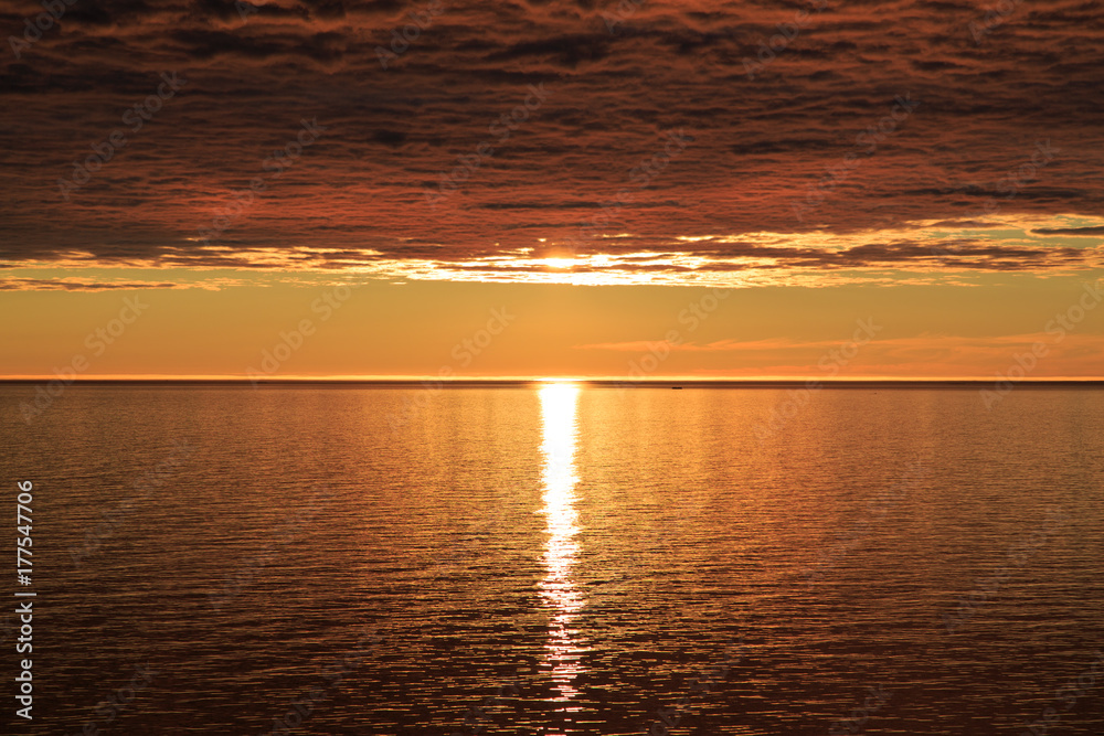 Sunset hidden by dense clouds and reflected in water Sunset hidden by dense clouds and reflected in water