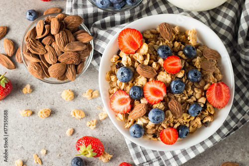 Healthy breakfast concept with oat flakes and fresh berries on rustic background. Food made of granola, muesli. Healthy banana smoothie with blackberries, muslie, strawberries, blueberries and honey. photo