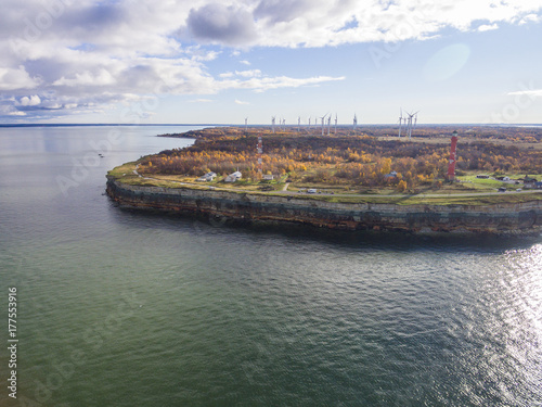 Old red Lighthouse in Paldiski, Estonia staying on a seacoast of Baltic Sea with the green energy windmills on the background