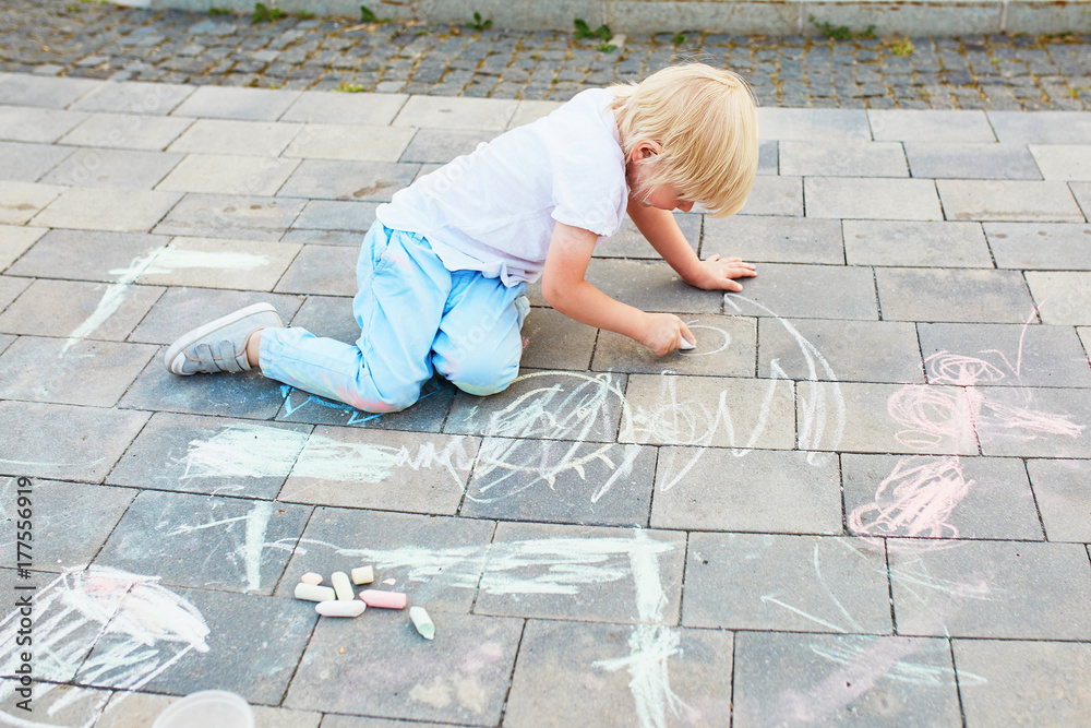 Little boy drawing with chalks on asphalt Little boy drawing with chalks on asphalt