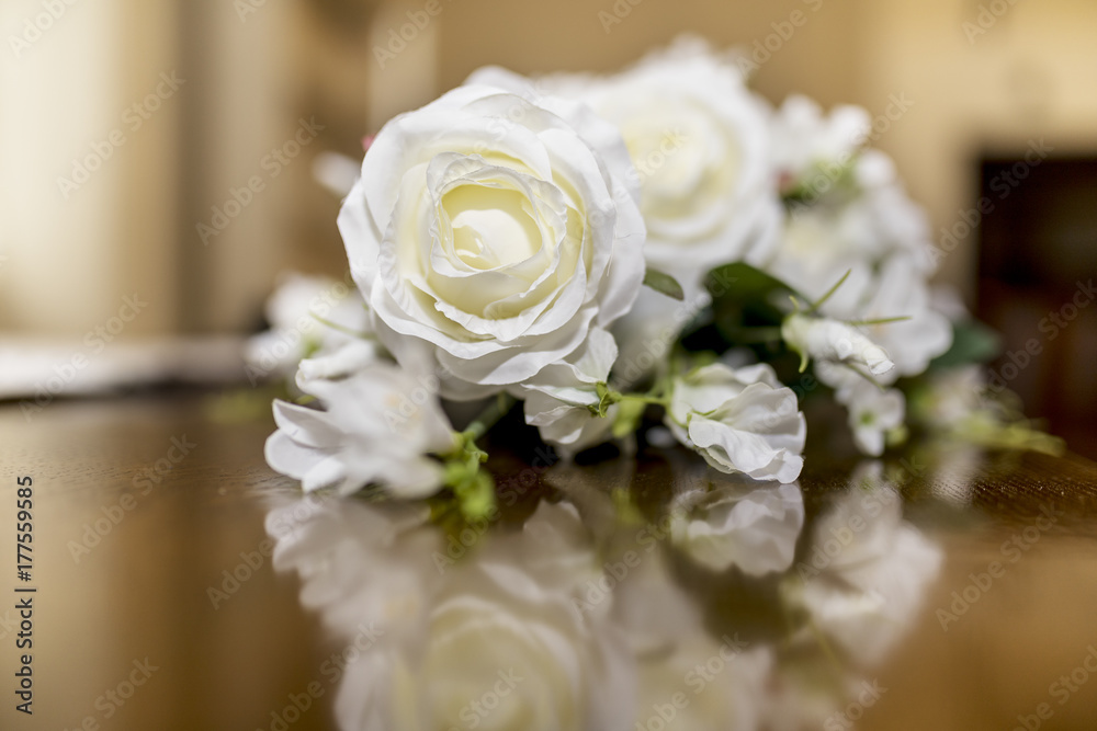 Obraz premium White roses wedding bouquet of flowers shot close up on a wooden table with a shallow depth of field at a tradtional English Wedding