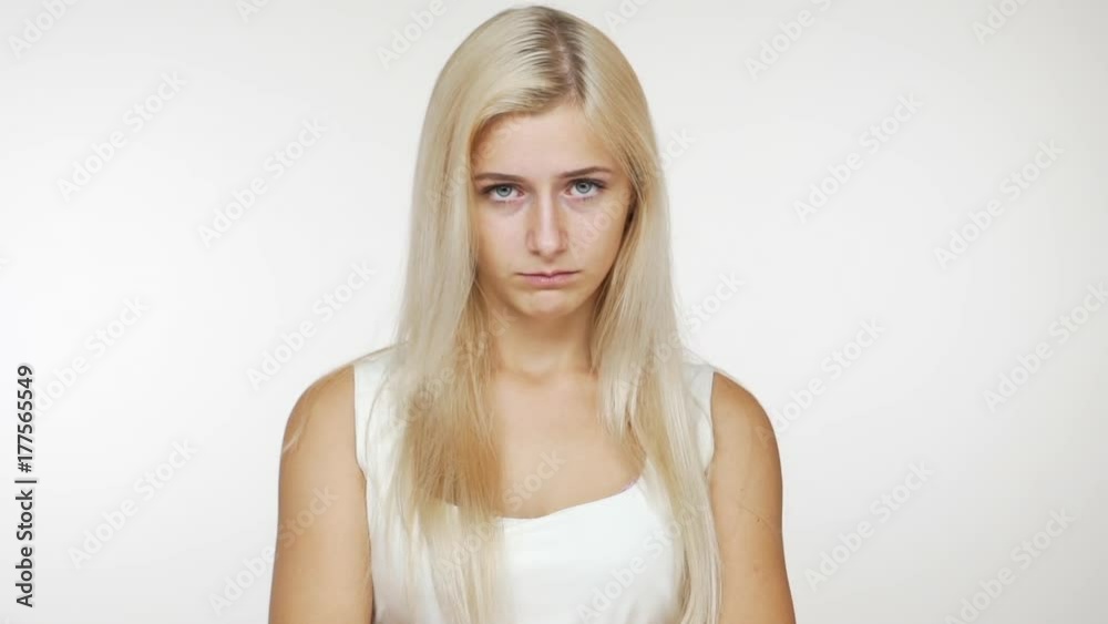 slow motion caucasian attractive blondie girl looking at camera being hurt pouting waving head negatively over white background. Concept of emotions