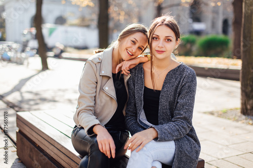 Two girls sit on the bench and lauch to camera