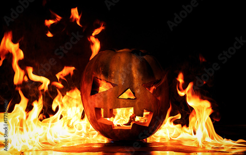 The concept of Halloween. The evil terrible pumpkin is burning in the hellish tongues of flame. Jack Lantern in the middle of the fire