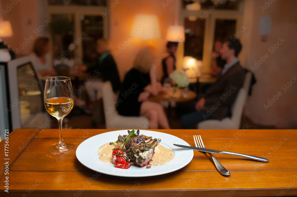 Lamb with potatoes and mushrooms sauce in the french restaurant and a wine glass.