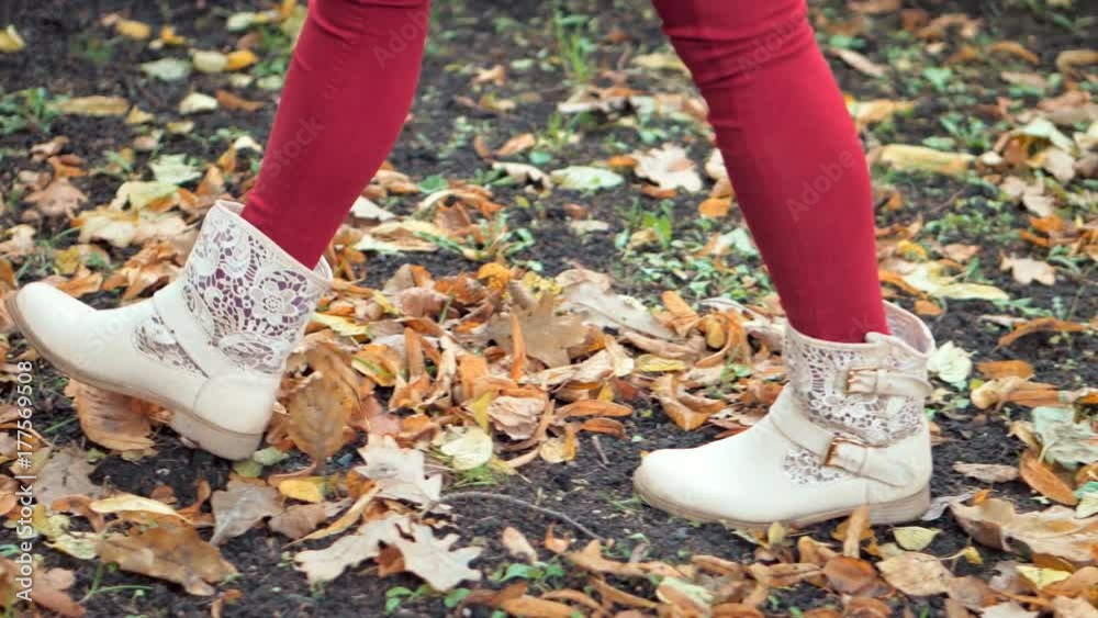 Young woman walking in autumn park on yellow leaves Young woman walking in autumn park on yellow leaves
